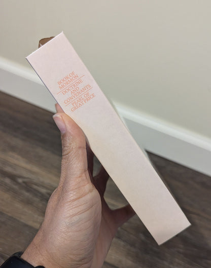 Hand holding a rectangular product box with text on a wooden floor.