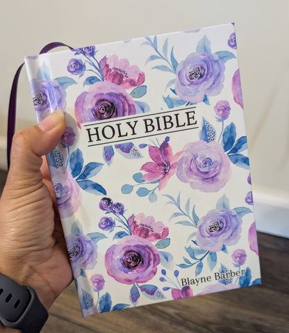 Floral-patterned Bible held by a person on a wooden surface