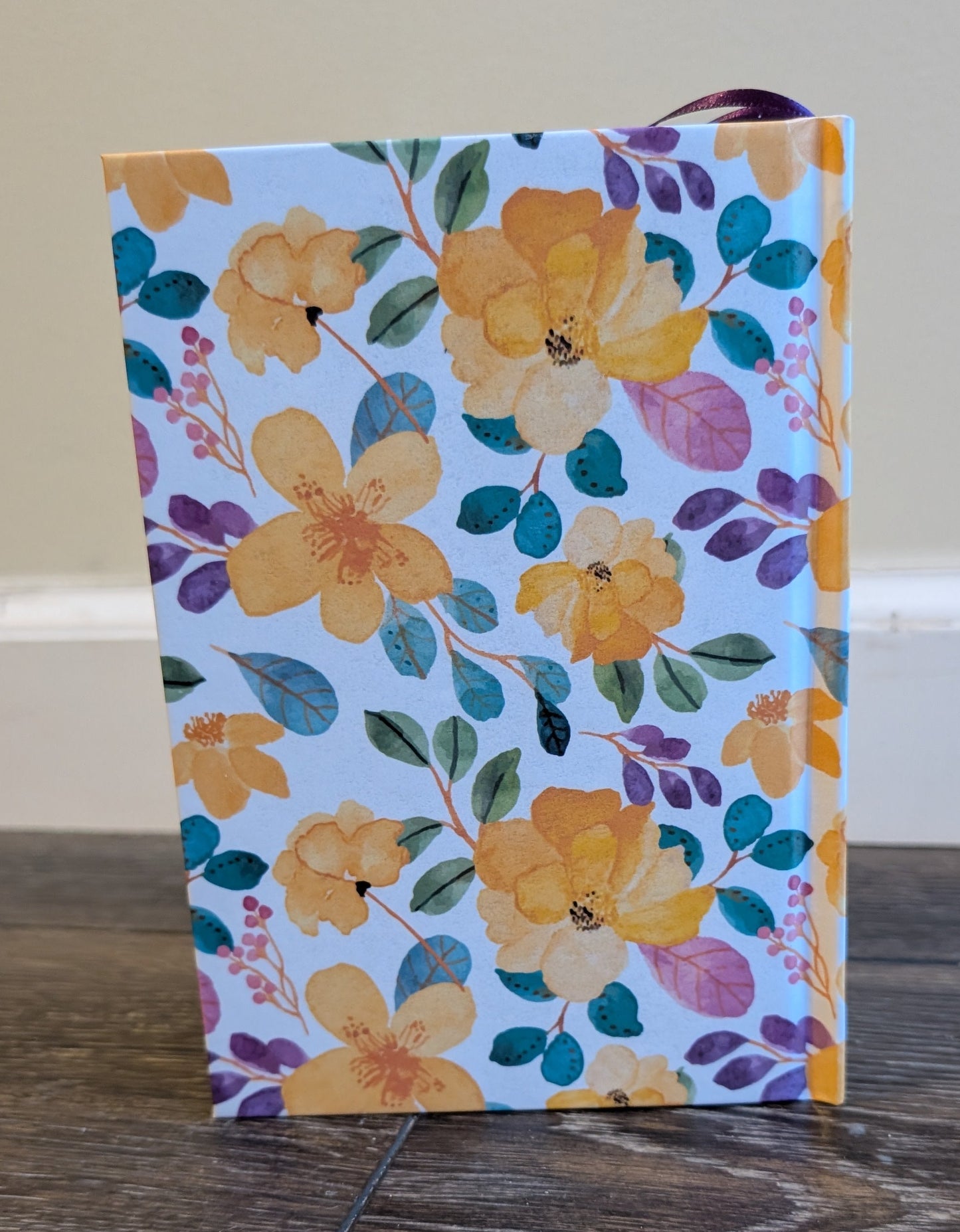 Floral-patterned notebook on a wooden surface with a neutral background