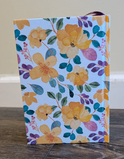 Floral-patterned notebook on a wooden surface with a neutral background