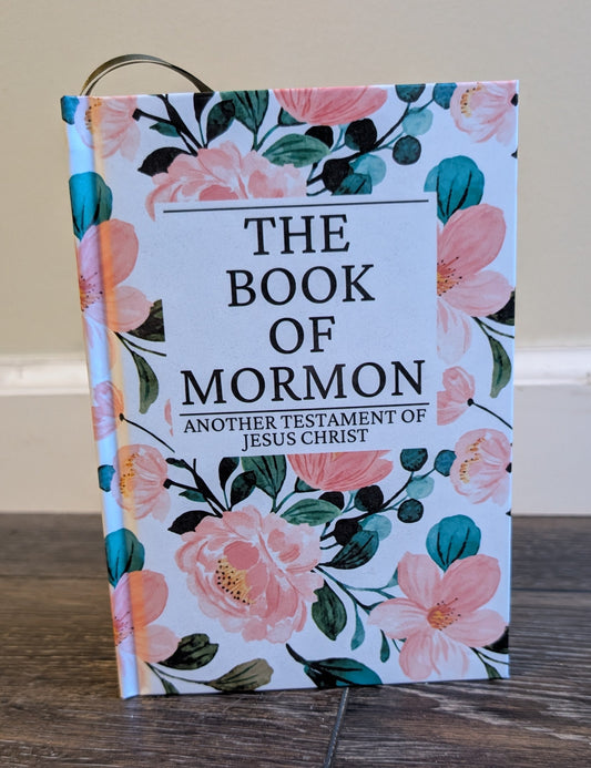 Floral-covered 'The Book of Mormon' on a wooden surface with a neutral background