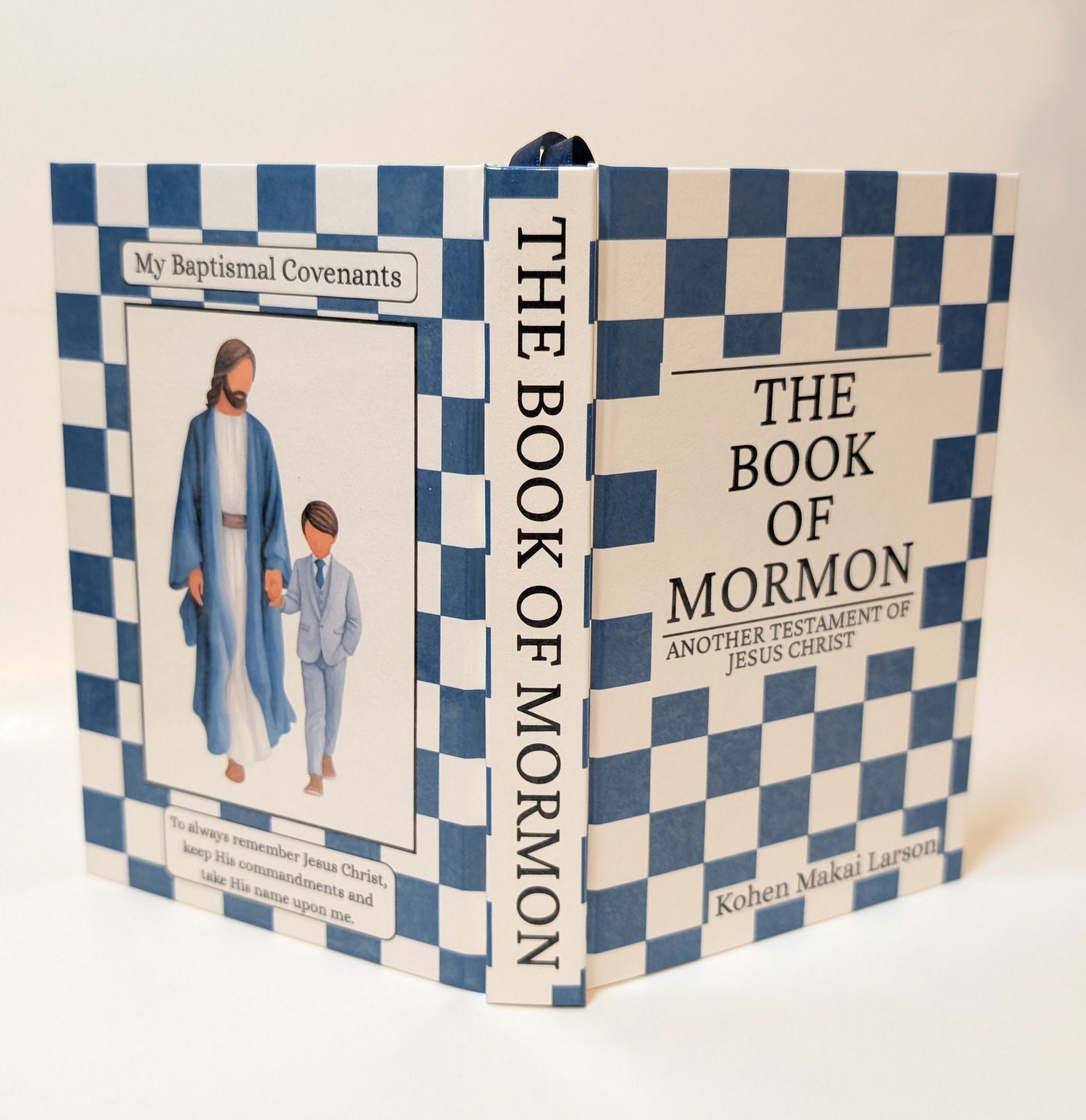 A hardcover book titled 'The Book of Mormon' with a blue and white checkered cover and spine, featuring an illustration of Jesus and a child on the front cover.